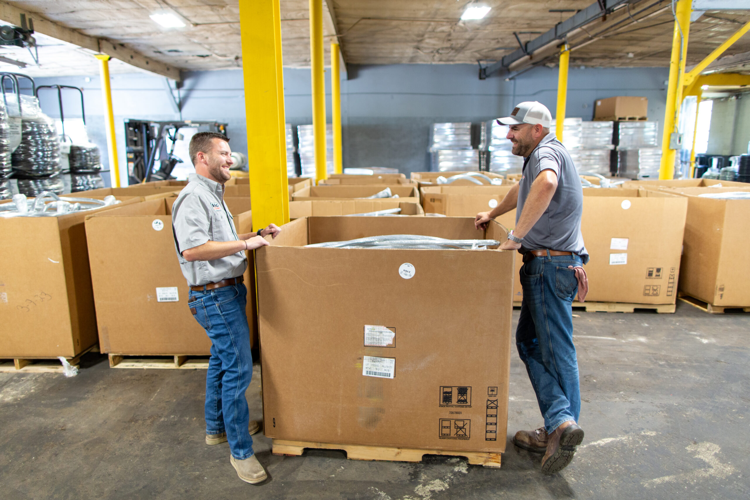 Two people standing over box of bailing wire talking